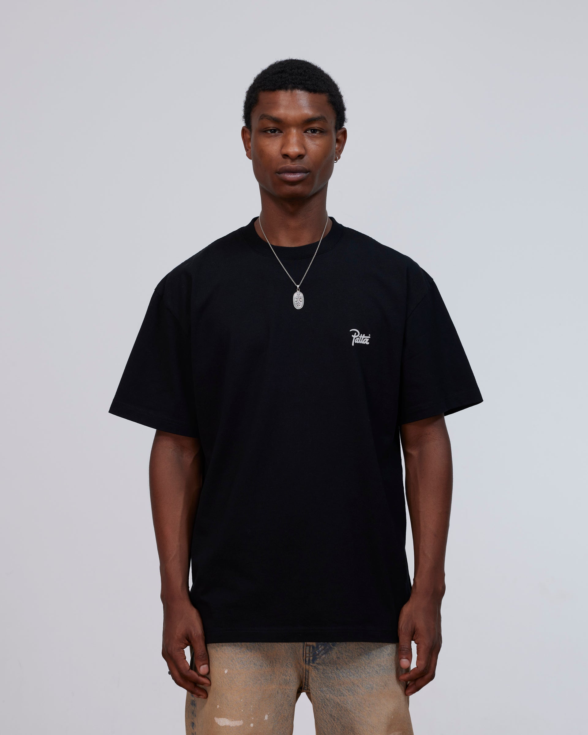 Front view of a model wearing the black Patta Charm cotton t-shirt with script logo on the chest.