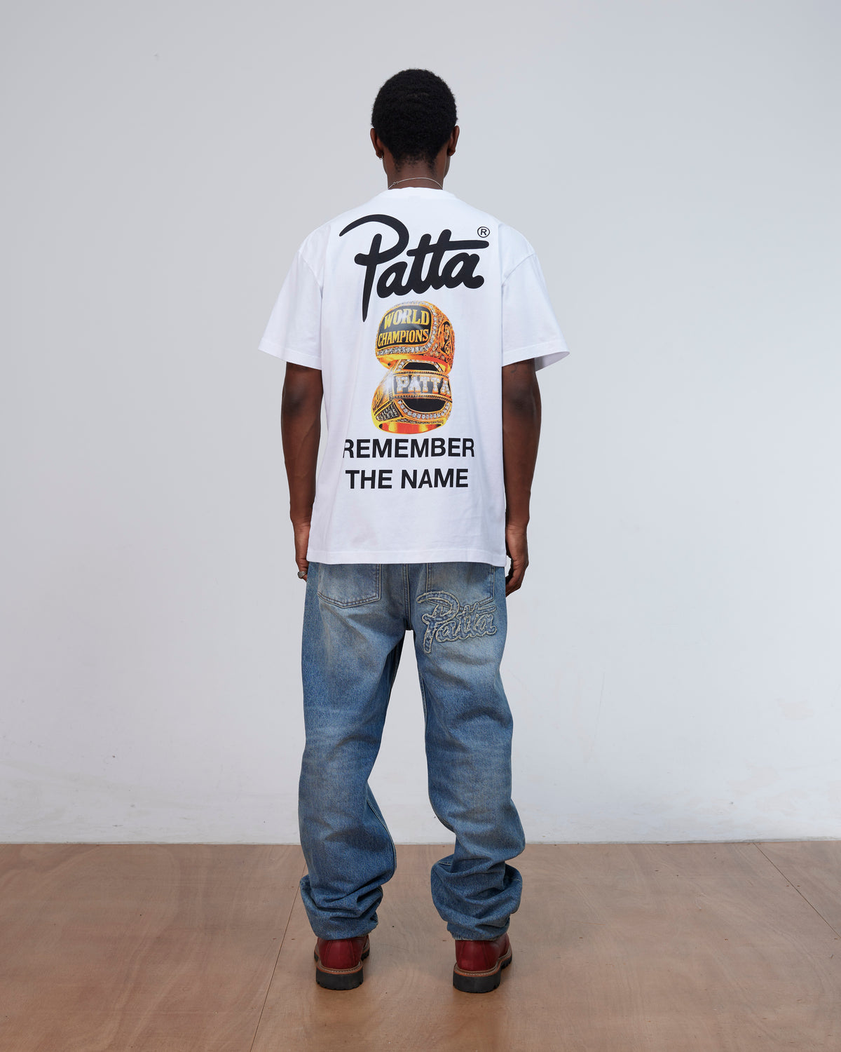 Back view of a model wearing the white Patta Championship T-Shirt with Remember The Name graphic.