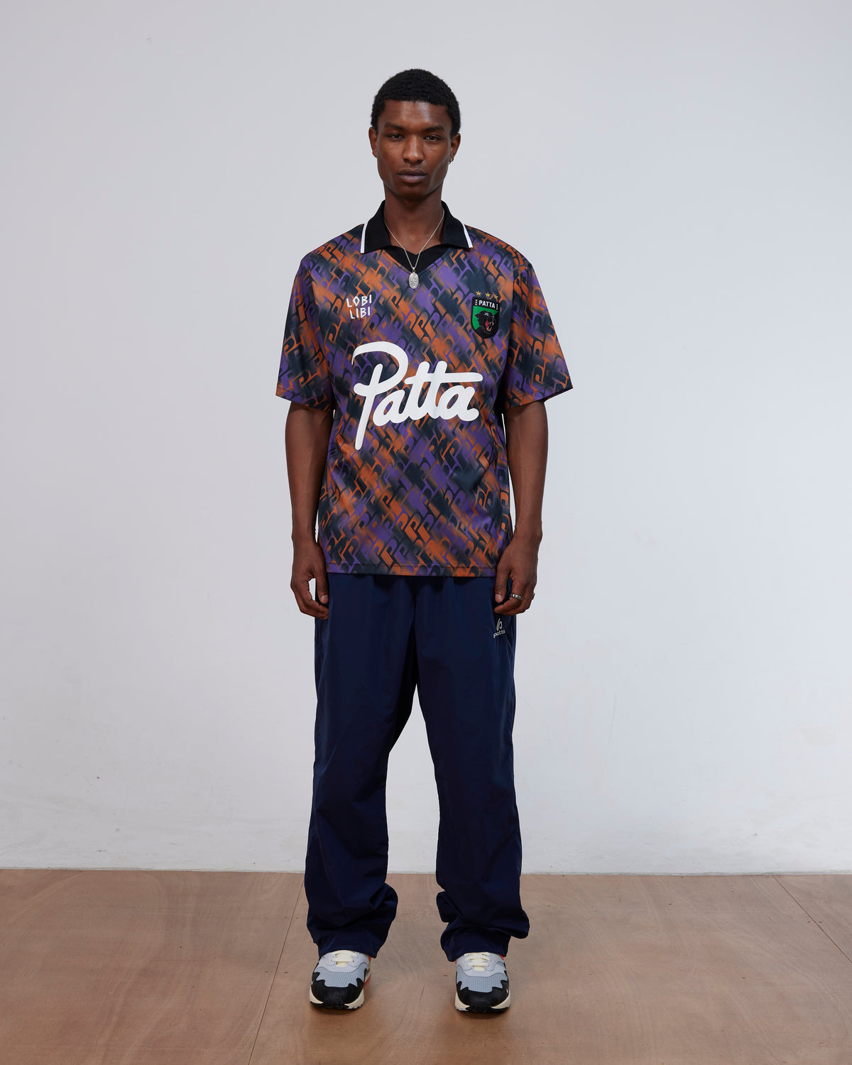 Model wearing the Patta All Over P Football Jersey in pansy purple and orange with navy trousers.