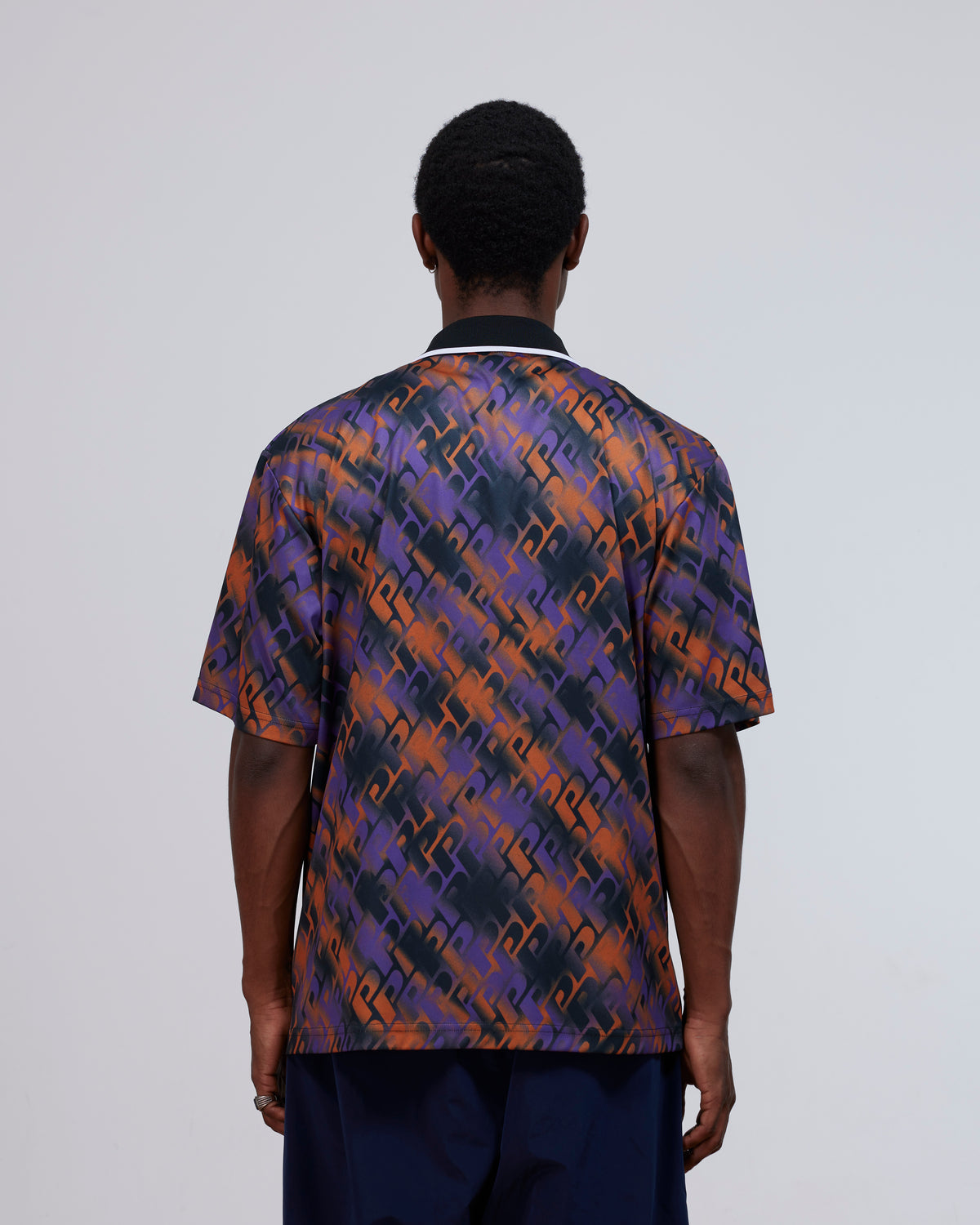 Back view of a model wearing the Patta All Over P Football Jersey in Pansy purple and orange.