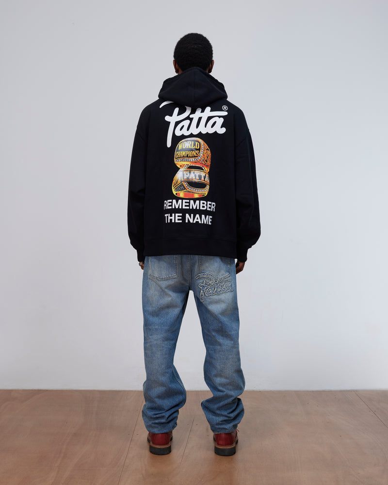 Back view of a model wearing the black Patta Championship Hooded Sweater with back graphic print.