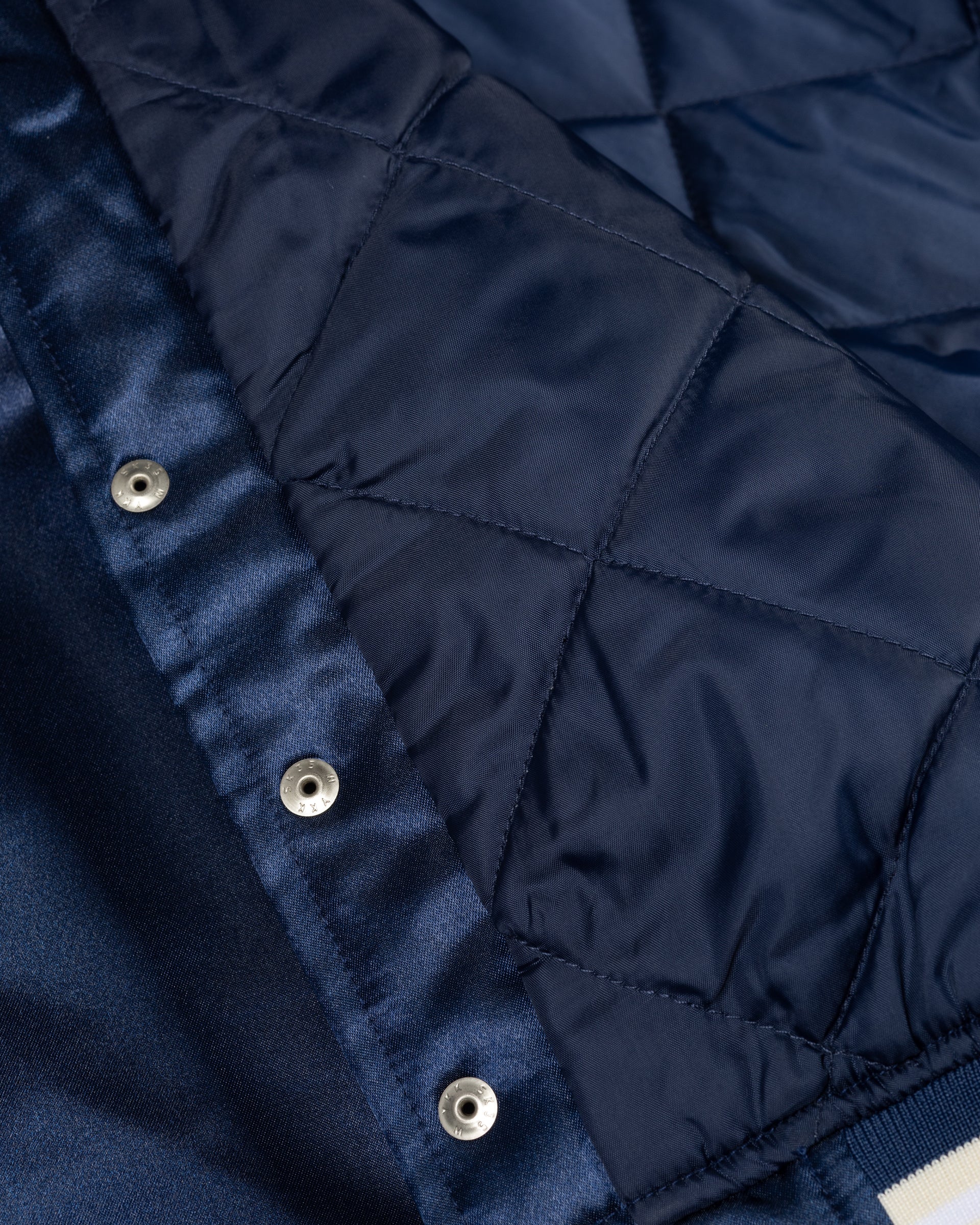 Close-up of the quilted lining and snap buttons on the Patta Kids Satin Bomber Jacket in Black Iris.